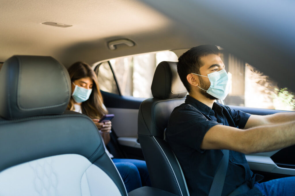 Handsome man driving a car and working as a rideshare driver during the coronavirus pandemic