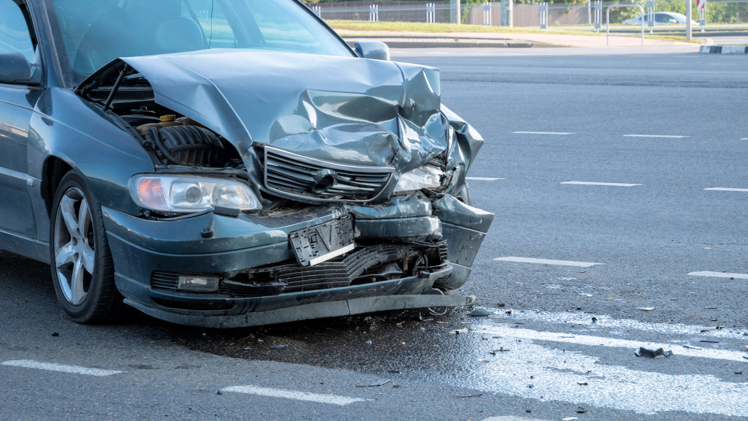 Front of dark color car damaged and broken by accident on the road.