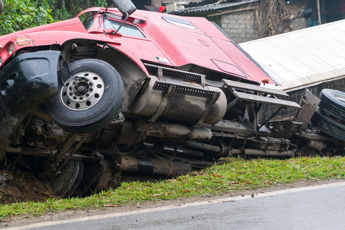 Accident on mountainous road, motor vehicle accident, car wreck. Long vehicle overturned and lying in ditch on side