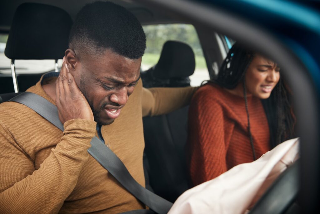 Person holding their neck in pain after a car accident, illustrating delayed injury symptoms